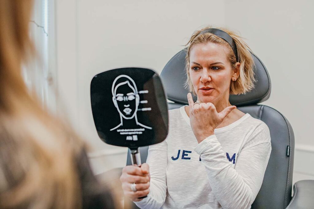 a woman examines her face during a free aesthetic consultation at DermaBlue