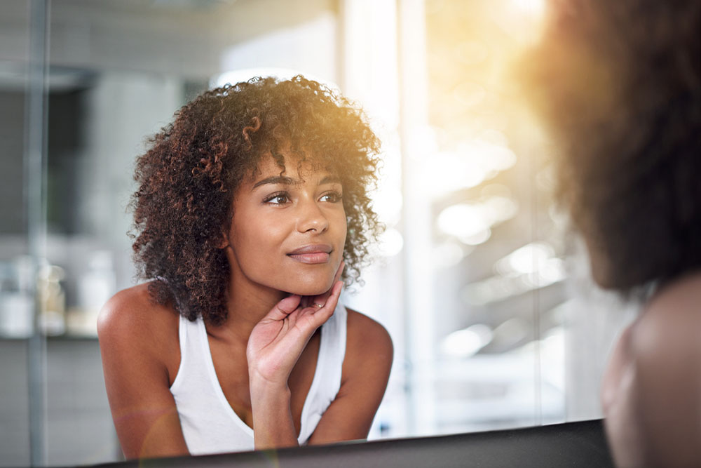 a woman examines skin after microneedling treatment in Asheville, North Carolina